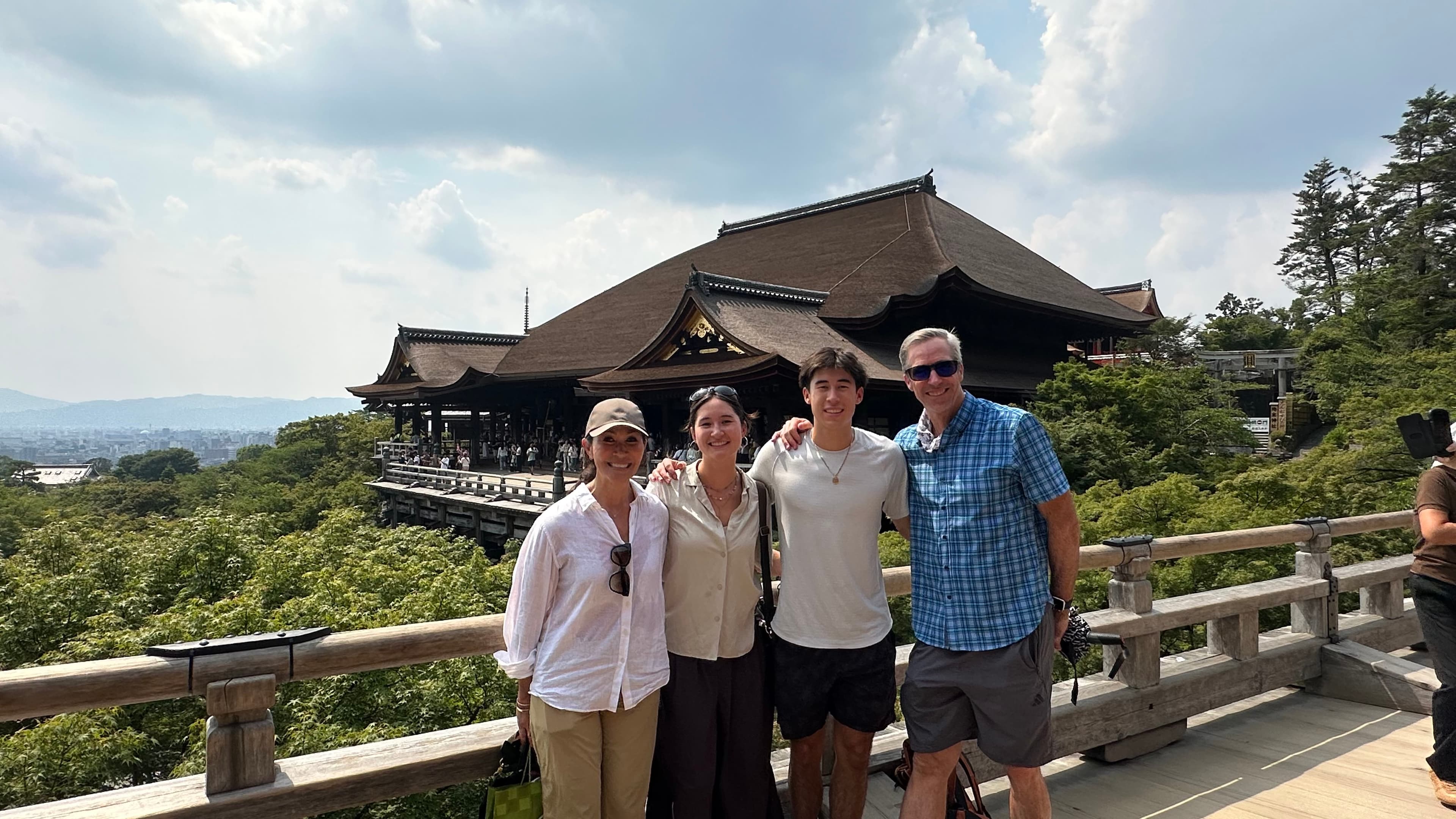 Guests visiting Kiyomizudera Temple with Kyoto's cityscape behind them.